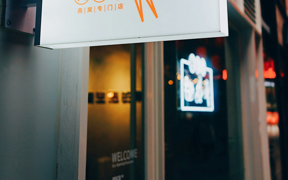Illuminated hanging storefront sign with a bird logo